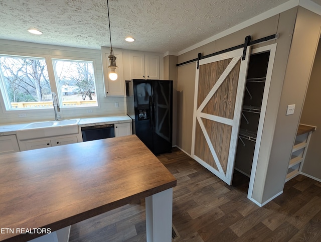 kitchen featuring pendant lighting, a barn door, white cabinetry, and black appliances