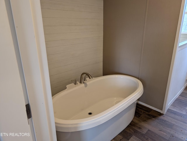 bathroom featuring wood-type flooring and a tub to relax in