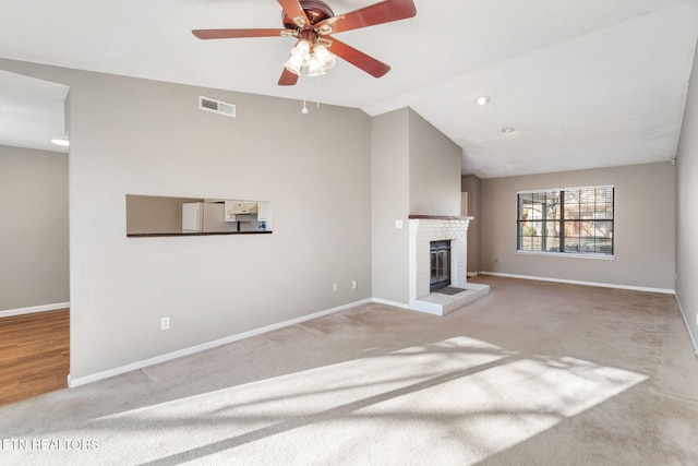 unfurnished living room featuring ceiling fan, a fireplace, light carpet, and lofted ceiling