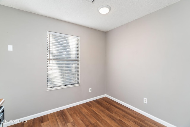 empty room with hardwood / wood-style floors and a textured ceiling