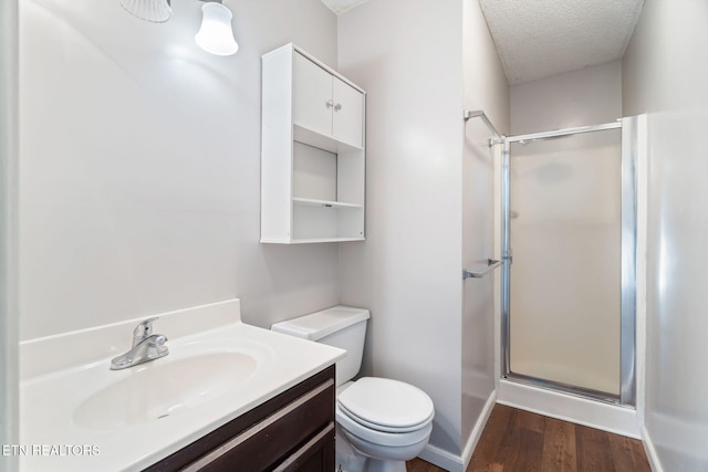 bathroom featuring a textured ceiling, vanity, hardwood / wood-style flooring, toilet, and a shower with shower door