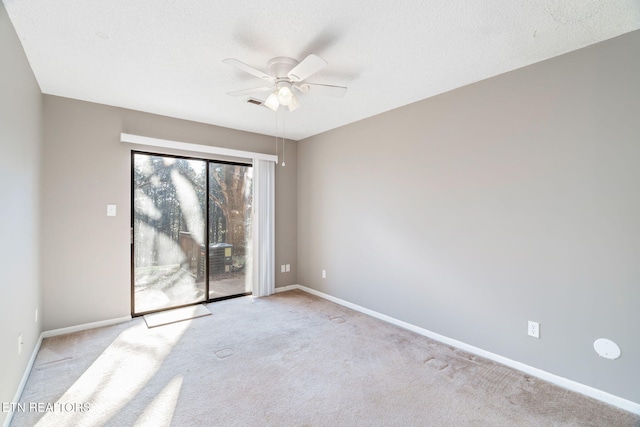 empty room with ceiling fan, light carpet, and a textured ceiling