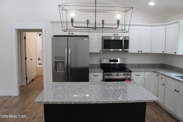 kitchen with light stone countertops, appliances with stainless steel finishes, decorative light fixtures, white cabinets, and a center island