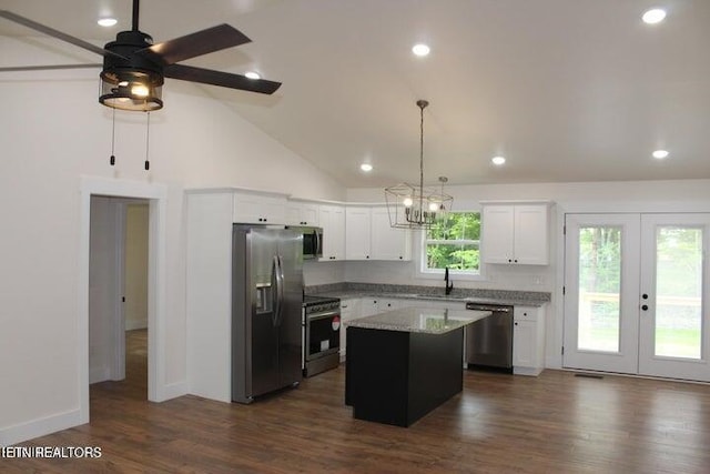 kitchen with sink, appliances with stainless steel finishes, hanging light fixtures, white cabinets, and a kitchen island