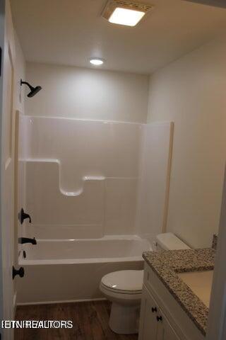 full bathroom with hardwood / wood-style floors, vanity, shower / bathtub combination, and toilet