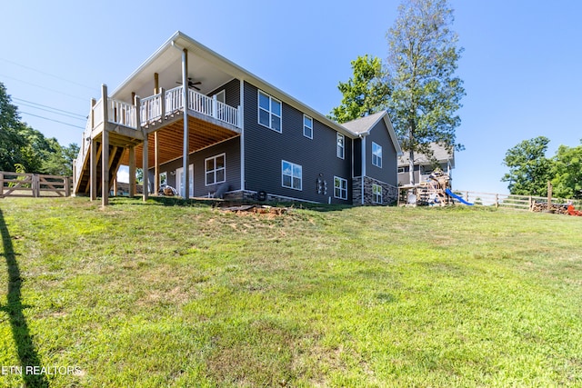 back of property featuring ceiling fan, a deck, and a lawn