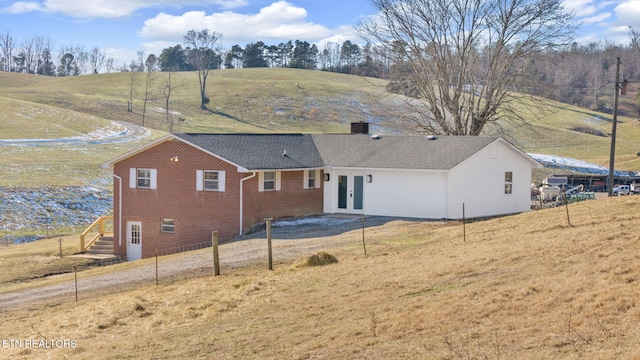 rear view of property with a yard, a rural view, and french doors