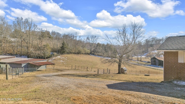 view of yard with an outbuilding, a rural view, and fence