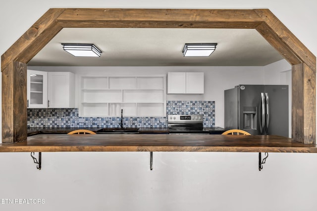 kitchen with wood counters, appliances with stainless steel finishes, open shelves, and a sink