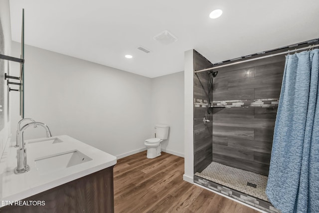 bathroom with visible vents, baseboards, toilet, wood finished floors, and a tile shower