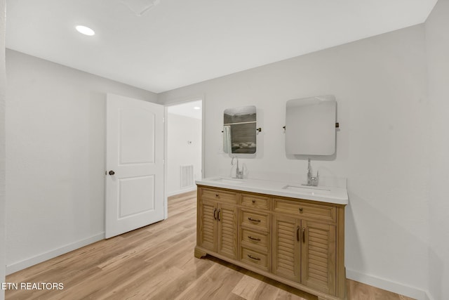 bathroom with wood finished floors, a sink, and baseboards