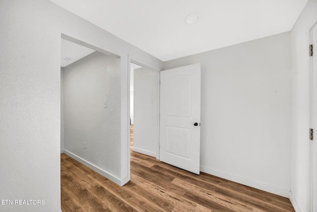 empty room with baseboards and wood finished floors