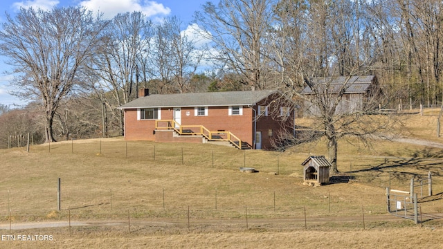 exterior space featuring a chimney, a rural view, fence, a front yard, and brick siding