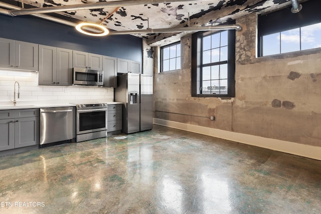 kitchen with gray cabinetry, decorative backsplash, sink, and stainless steel appliances