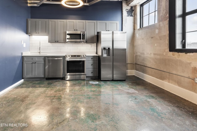 kitchen with gray cabinetry, sink, backsplash, a towering ceiling, and appliances with stainless steel finishes