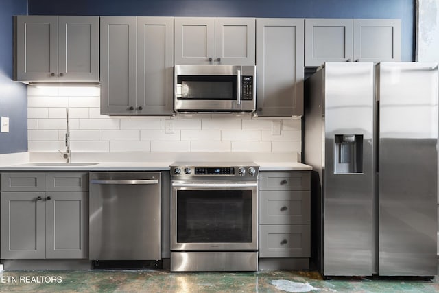 kitchen with decorative backsplash, appliances with stainless steel finishes, gray cabinetry, and sink