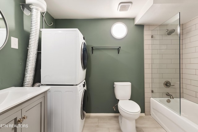 full bathroom featuring stacked washing maching and dryer, tile patterned floors, vanity, toilet, and tiled shower / bath