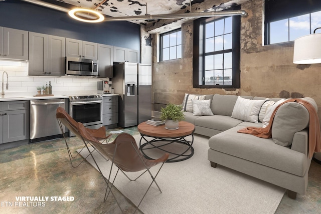 kitchen featuring decorative backsplash, appliances with stainless steel finishes, gray cabinetry, and sink