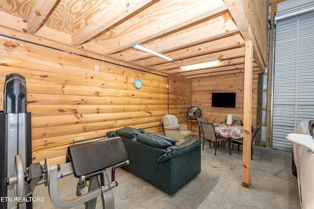 living room with rustic walls, beamed ceiling, and concrete flooring