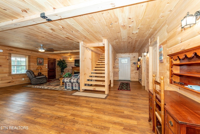 interior space with ceiling fan, hardwood / wood-style floors, wooden ceiling, and wood walls