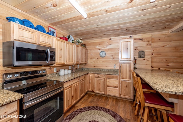 kitchen featuring light stone countertops, wooden walls, wooden ceiling, and appliances with stainless steel finishes