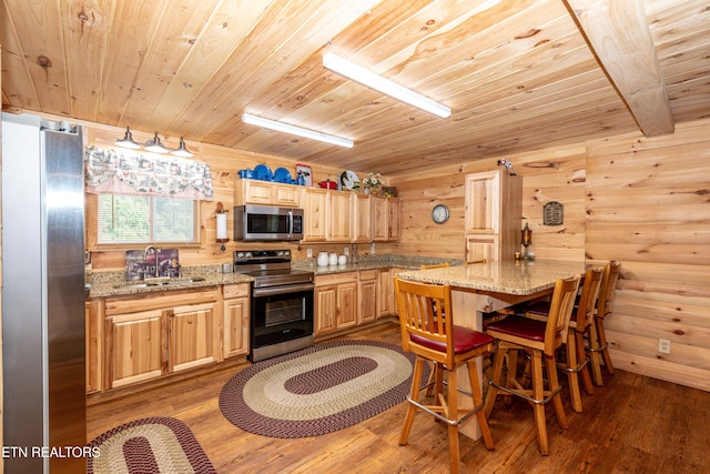 kitchen with wooden ceiling, sink, light stone countertops, rustic walls, and appliances with stainless steel finishes