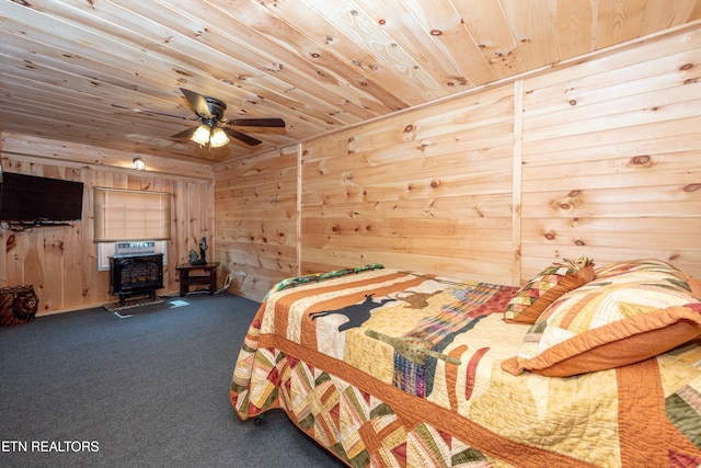 carpeted bedroom with a wood stove, wooden walls, ceiling fan, and wooden ceiling