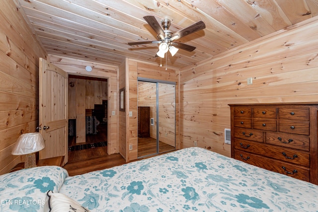 bedroom featuring ceiling fan, wood ceiling, wooden walls, and a closet