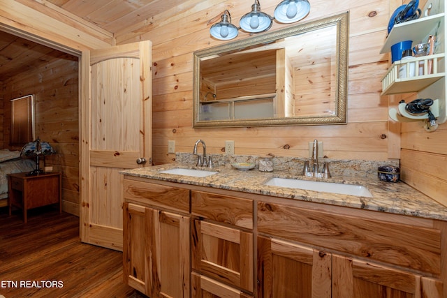 bathroom with hardwood / wood-style floors, vanity, and wooden walls