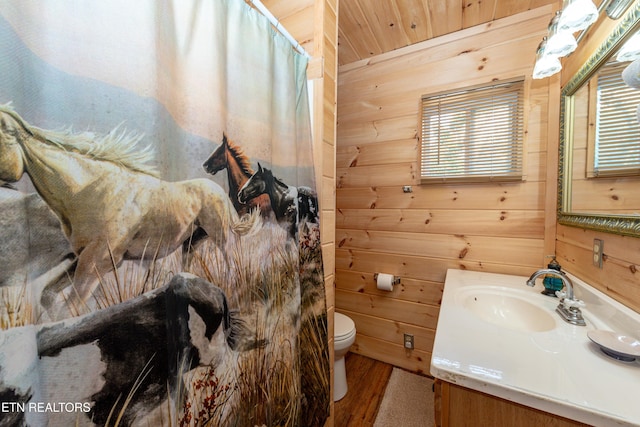 bathroom featuring wooden walls, hardwood / wood-style floors, vanity, and toilet