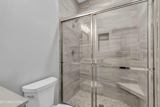 bathroom featuring toilet and a shower with shower door