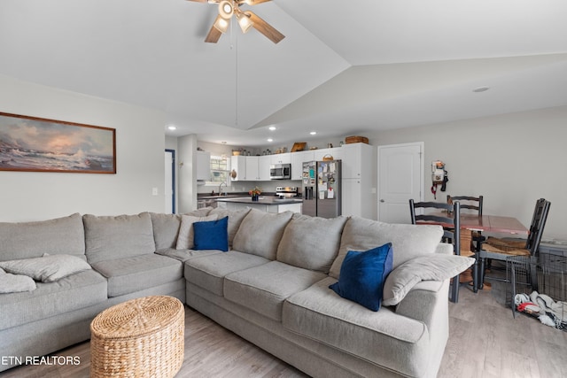 living room featuring ceiling fan, light hardwood / wood-style floors, and lofted ceiling