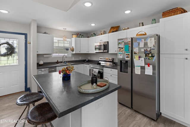 kitchen featuring a breakfast bar, light hardwood / wood-style flooring, appliances with stainless steel finishes, a kitchen island, and white cabinetry