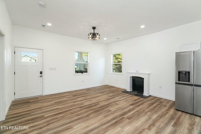 unfurnished living room featuring light hardwood / wood-style flooring and an inviting chandelier