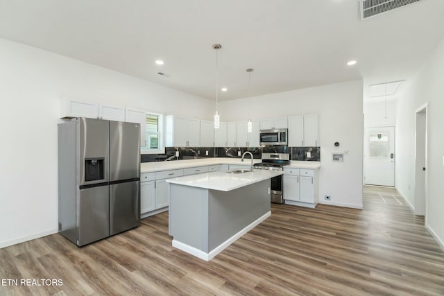 kitchen featuring stainless steel appliances, white cabinetry, and an island with sink