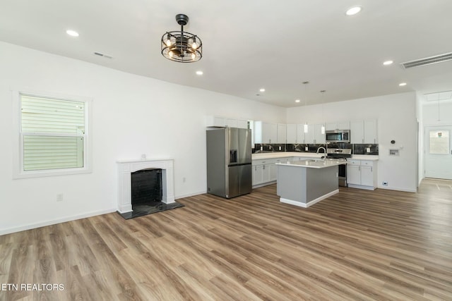 kitchen with appliances with stainless steel finishes, white cabinetry, and decorative light fixtures