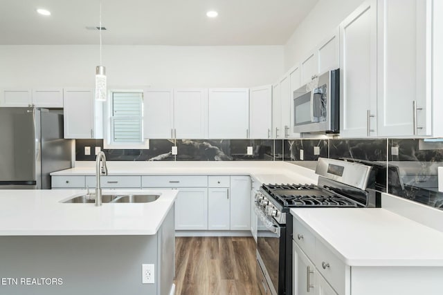 kitchen with decorative light fixtures, appliances with stainless steel finishes, white cabinetry, and sink