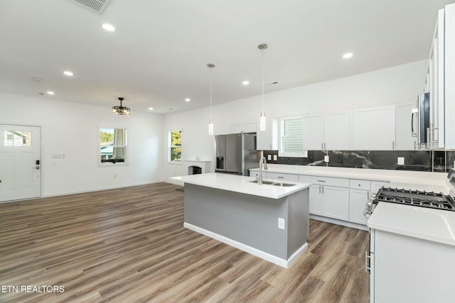 kitchen with sink, white cabinets, a center island with sink, pendant lighting, and appliances with stainless steel finishes