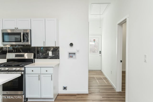 kitchen featuring appliances with stainless steel finishes, light hardwood / wood-style floors, white cabinetry, and tasteful backsplash