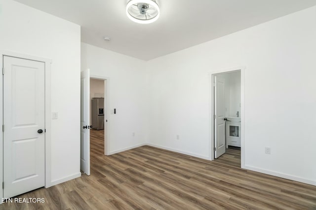 unfurnished bedroom with stainless steel fridge with ice dispenser and dark hardwood / wood-style floors