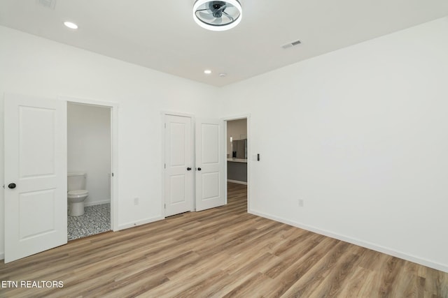 unfurnished bedroom featuring connected bathroom and wood-type flooring