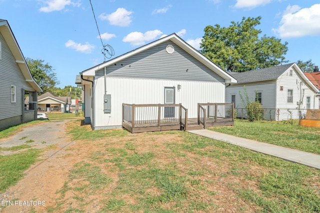 rear view of property featuring a lawn and a wooden deck