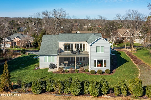 rear view of property featuring a lawn, a patio area, a sunroom, and a balcony