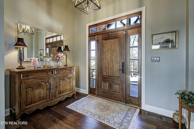 foyer entrance featuring an inviting chandelier and dark wood-type flooring