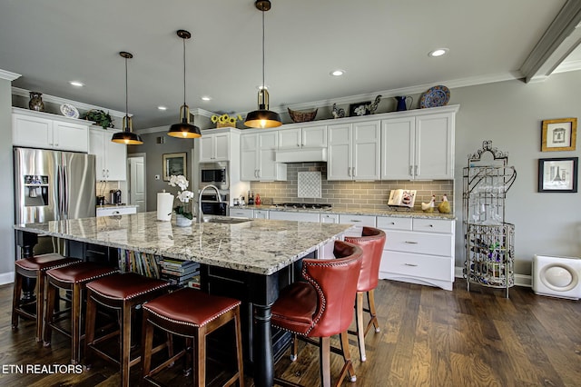 kitchen with sink, a large island with sink, pendant lighting, white cabinets, and a breakfast bar area