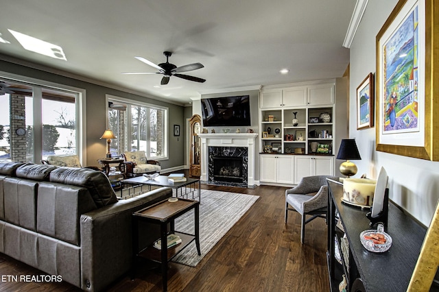 living room featuring ceiling fan, a high end fireplace, dark wood-type flooring, and ornamental molding