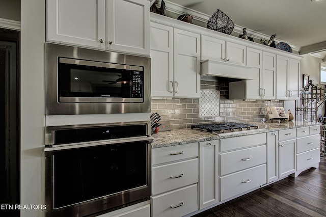 kitchen with tasteful backsplash, white cabinets, and stainless steel appliances