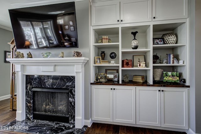 interior space with built in shelves, white cabinetry, a fireplace, and dark hardwood / wood-style floors