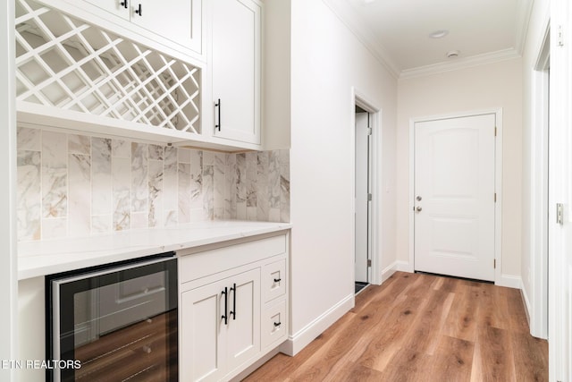 kitchen featuring tasteful backsplash, crown molding, white cabinetry, light hardwood / wood-style flooring, and wine cooler