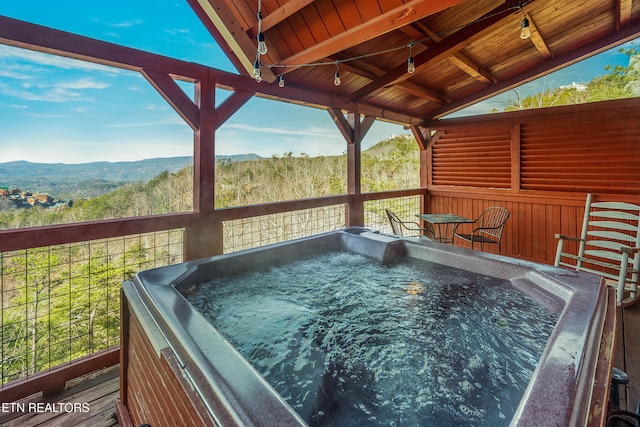 wooden terrace with a hot tub and a mountain view